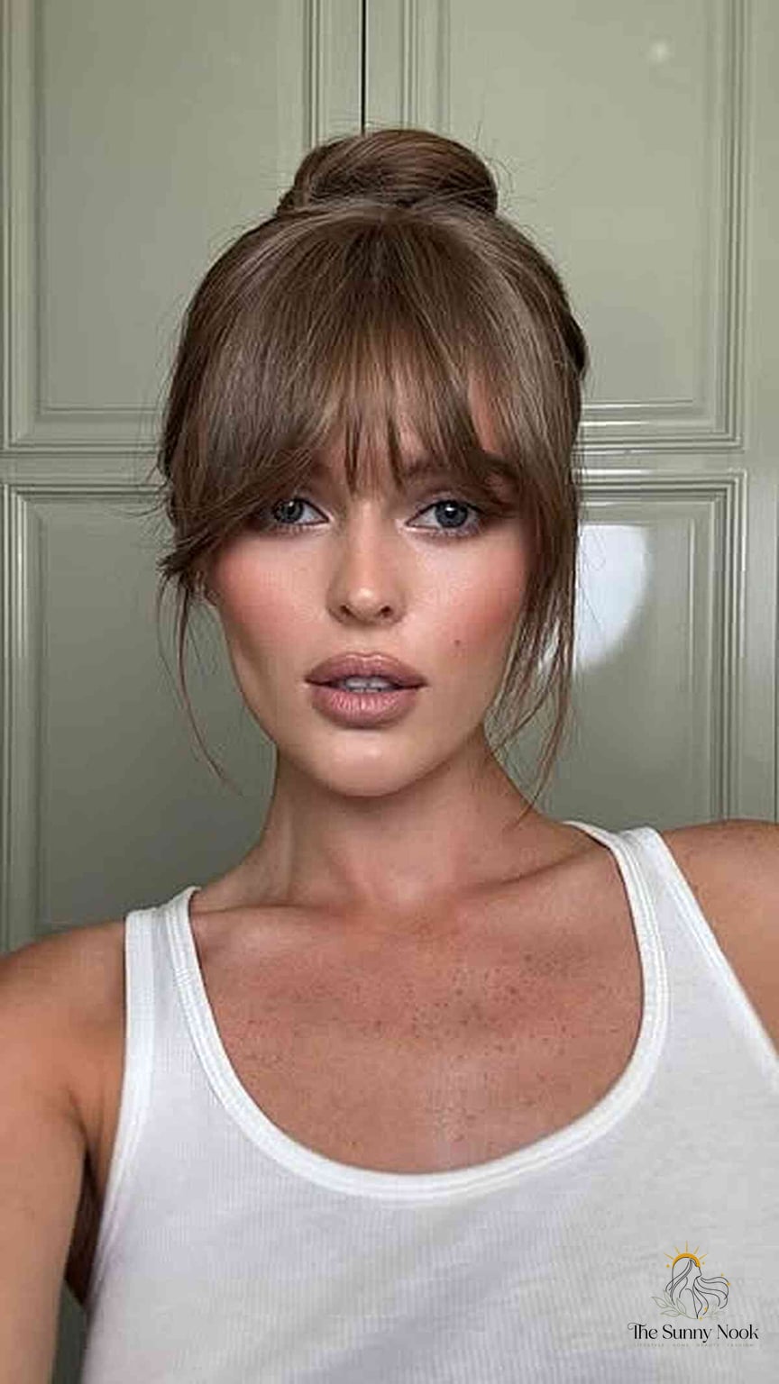 27 Slick Bun Hairstyles We're Obsessed With Right Now 15 Sleek Top Knot with Curtain Bangs